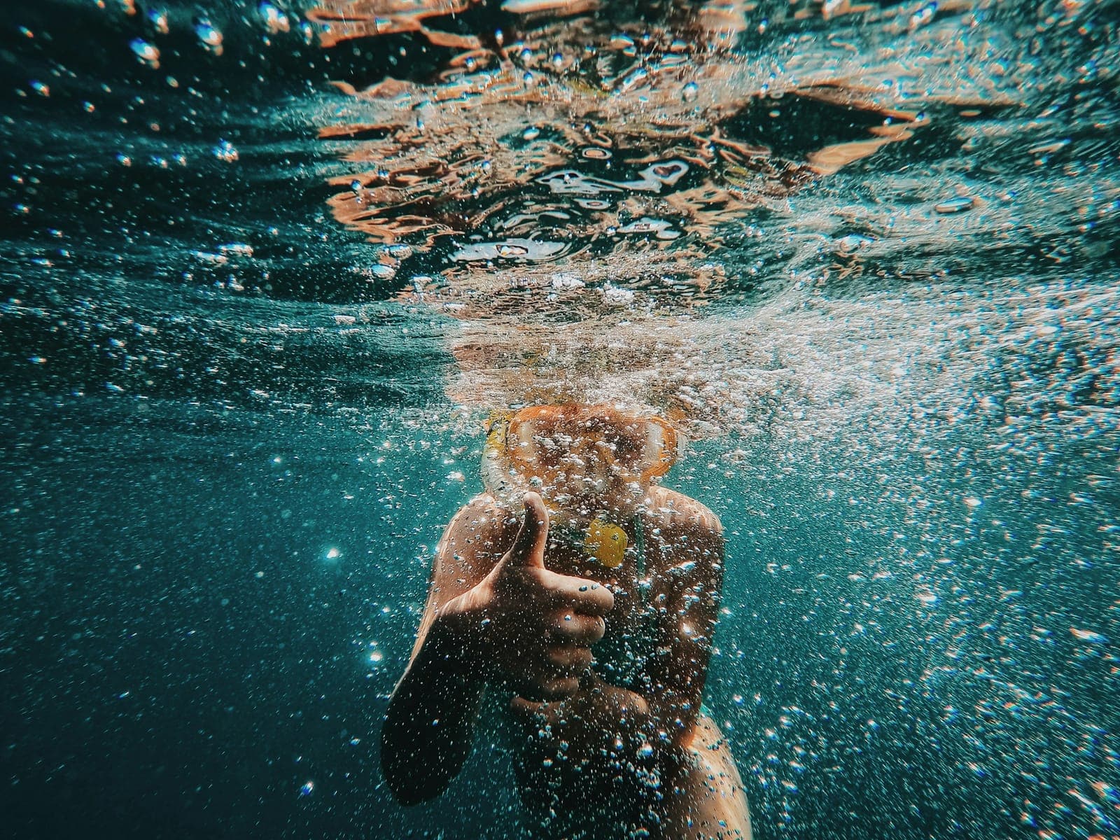 A boy in goggles swimming underwater in clear water